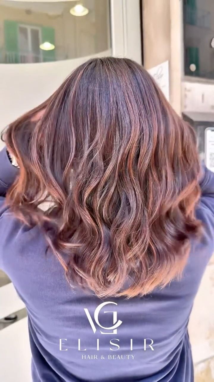 Una donna con lunghi capelli castani indossa una maglietta blu.