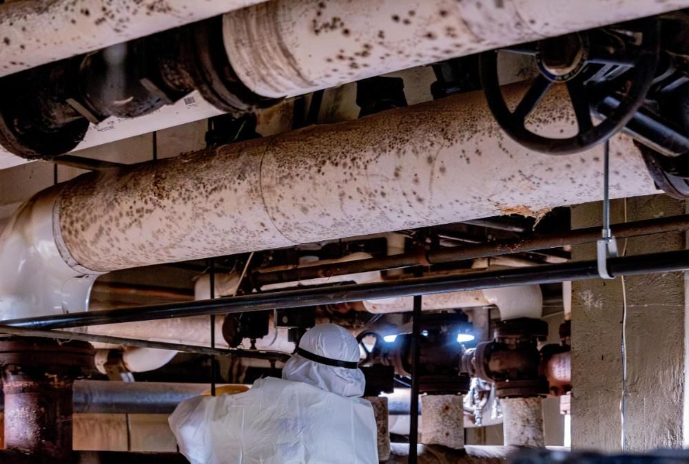 A man in a protective suit for asbestos pipe insulation