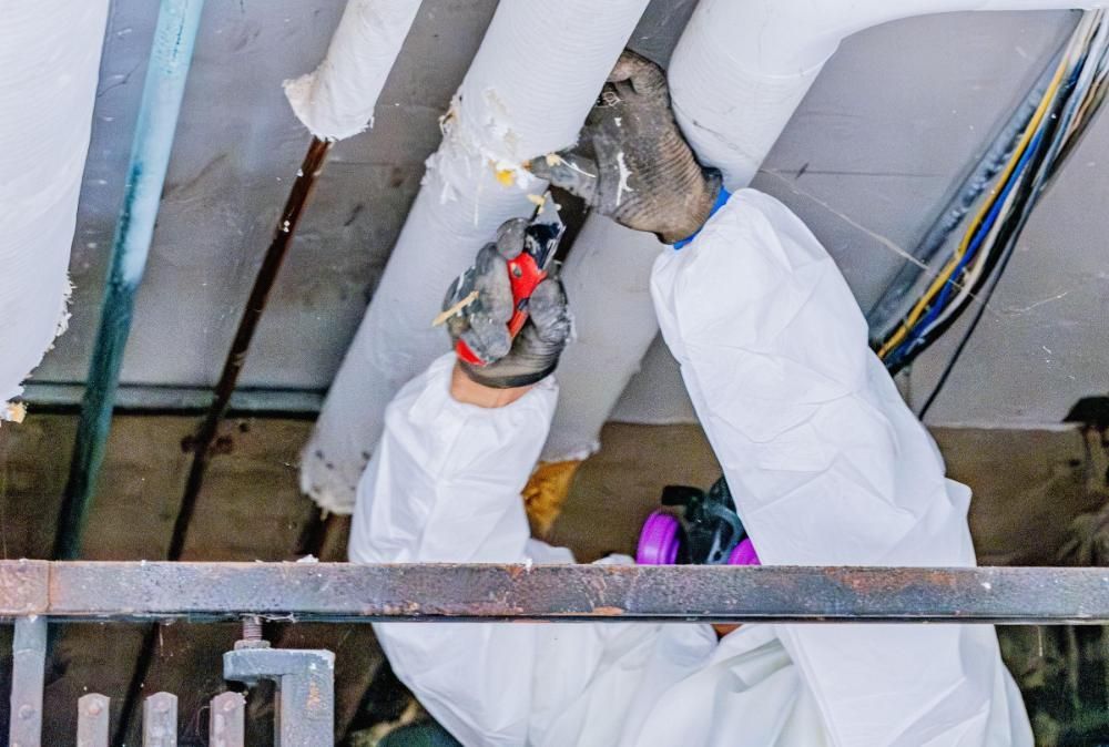 A man in a protective suit is working on a pipe.