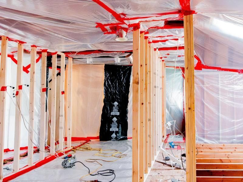 A room under construction with wooden beams and plastic covering.