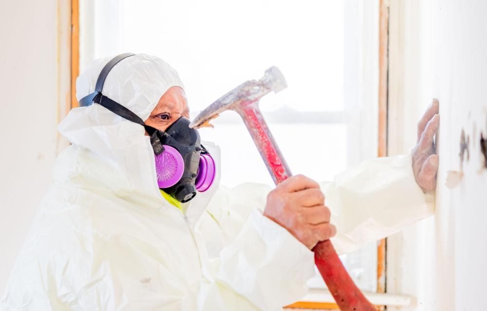 A man in a protective suit and mask is holding a hammer.