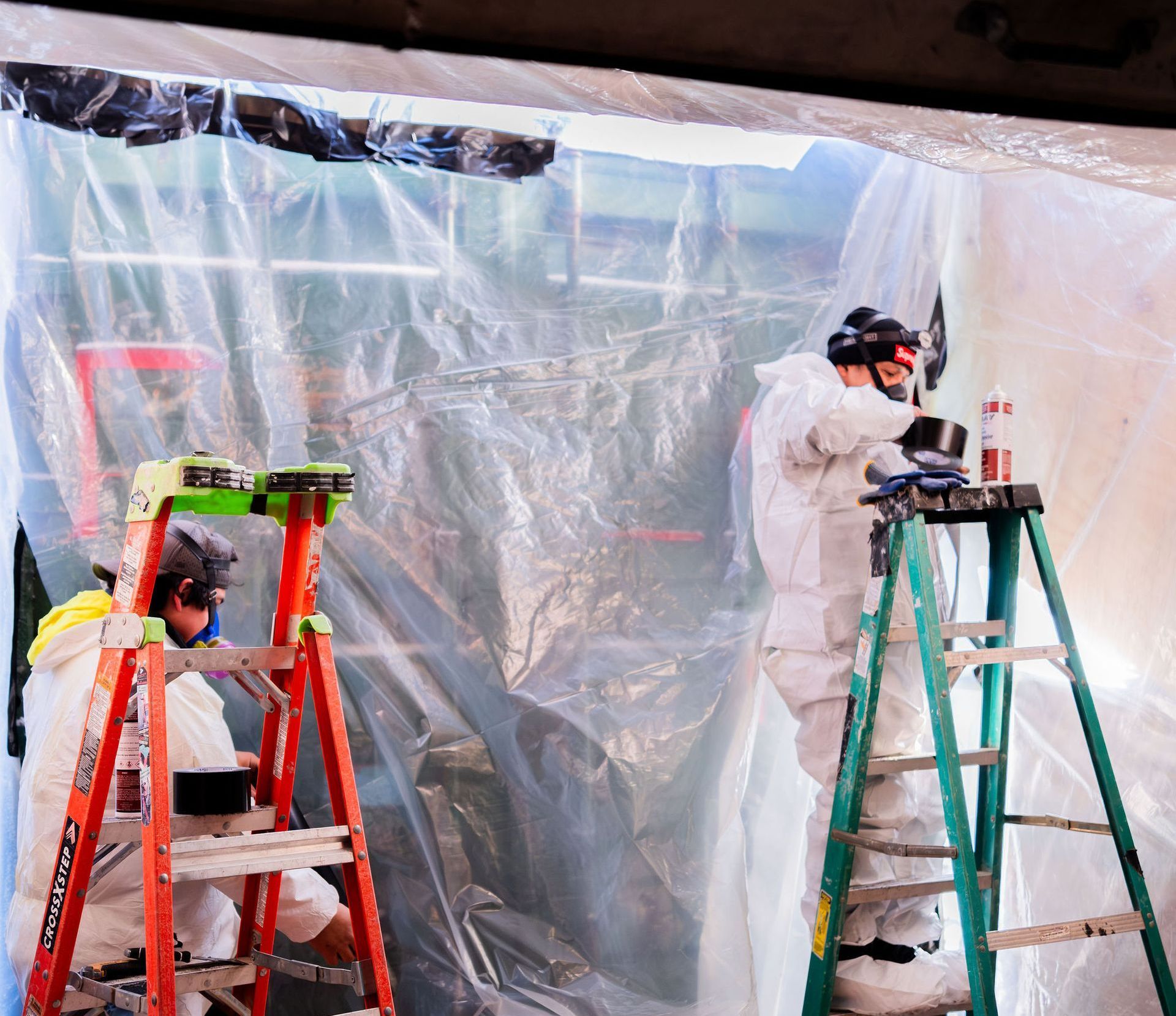 Two men taping off an area for lead paint removal