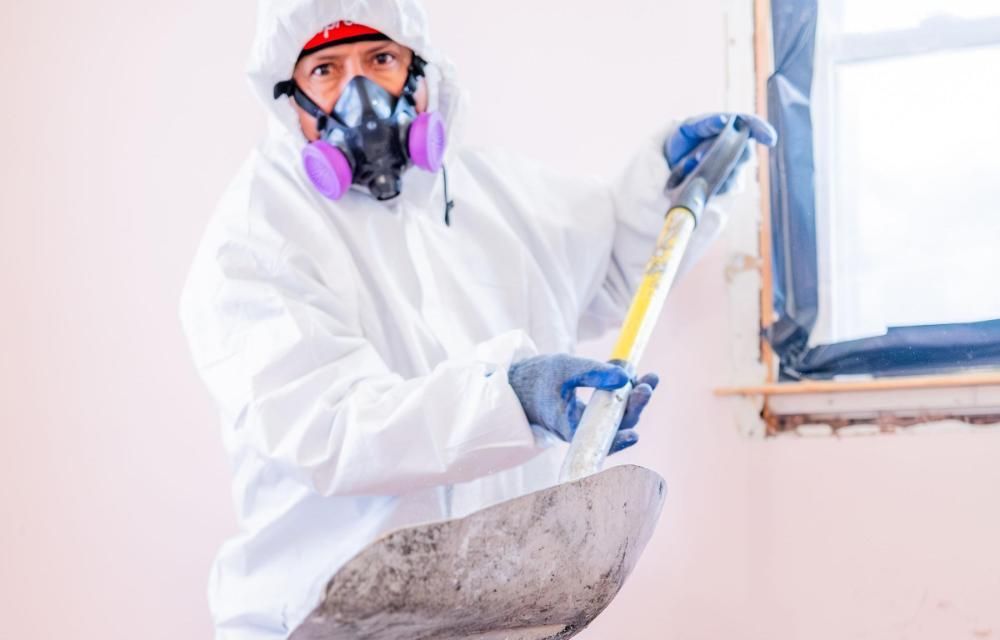 A man in a protective suit and mask removing debris