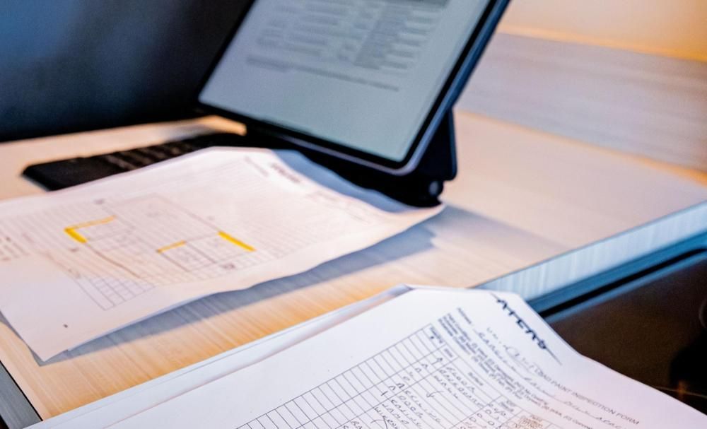 A tablet is sitting on a desk next to a bunch of papers.