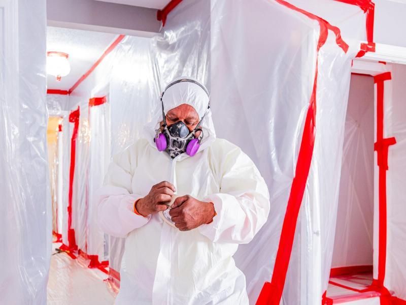 A man in a protective suit and mask is standing in a hallway.