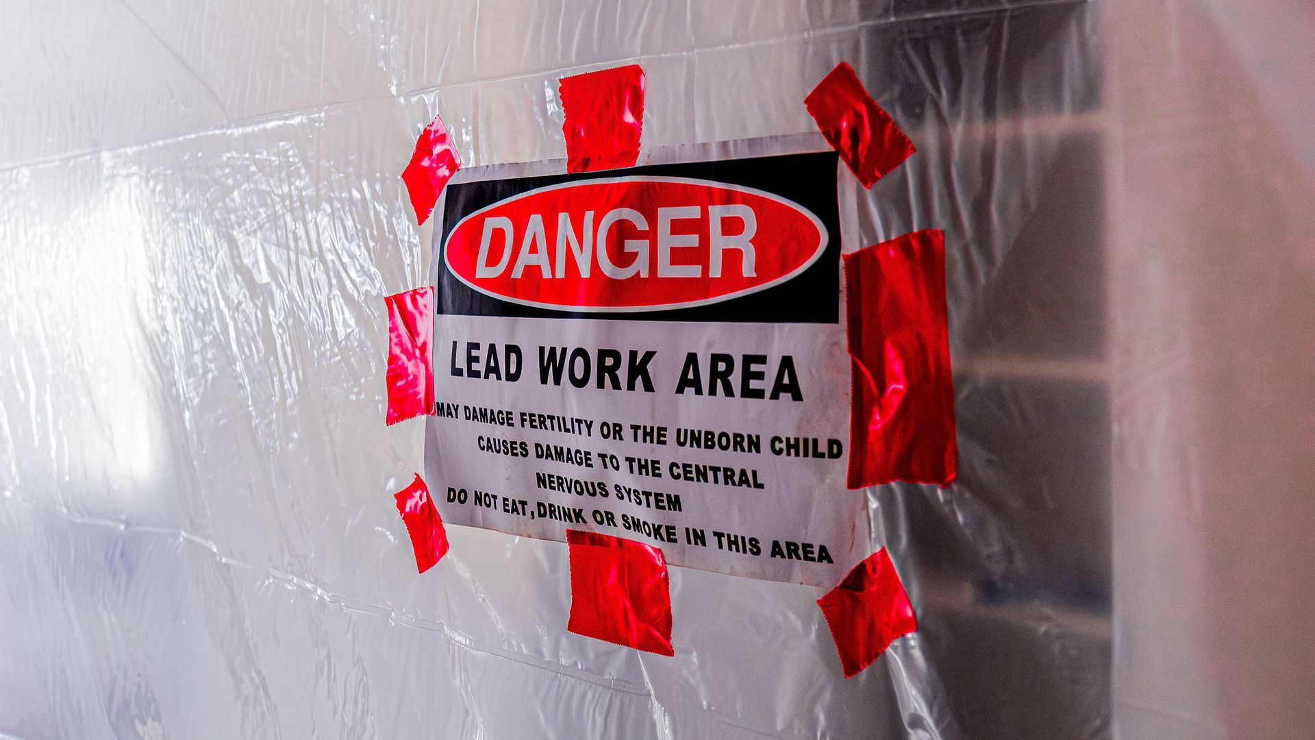 A sign that says danger lead work area is taped to a wall.