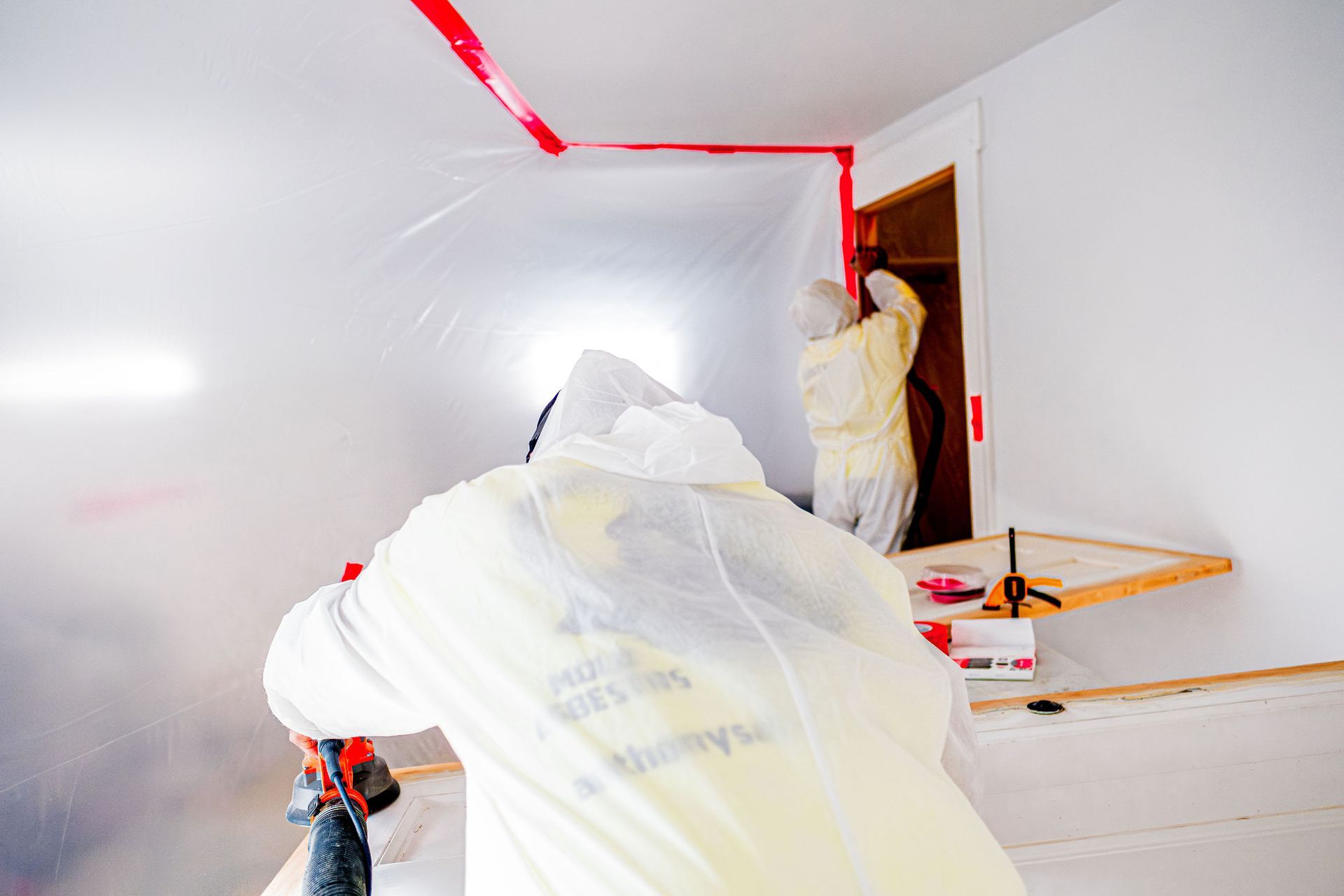 A man in a protective suit is working in a room.