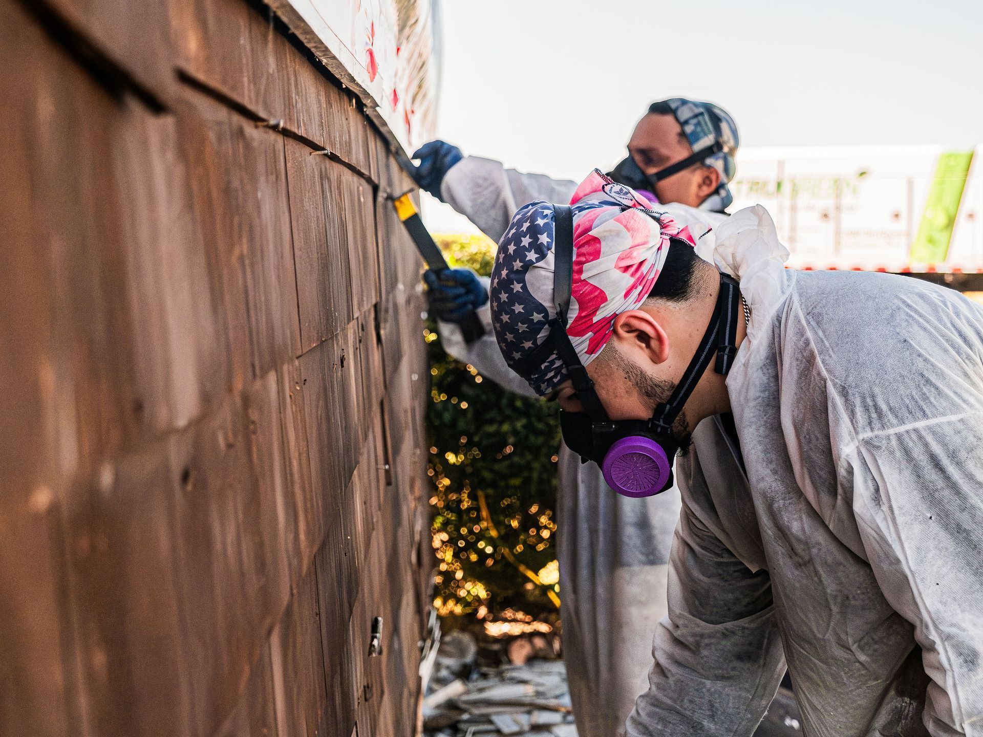 A couple of people are working on a removing asbestos siding