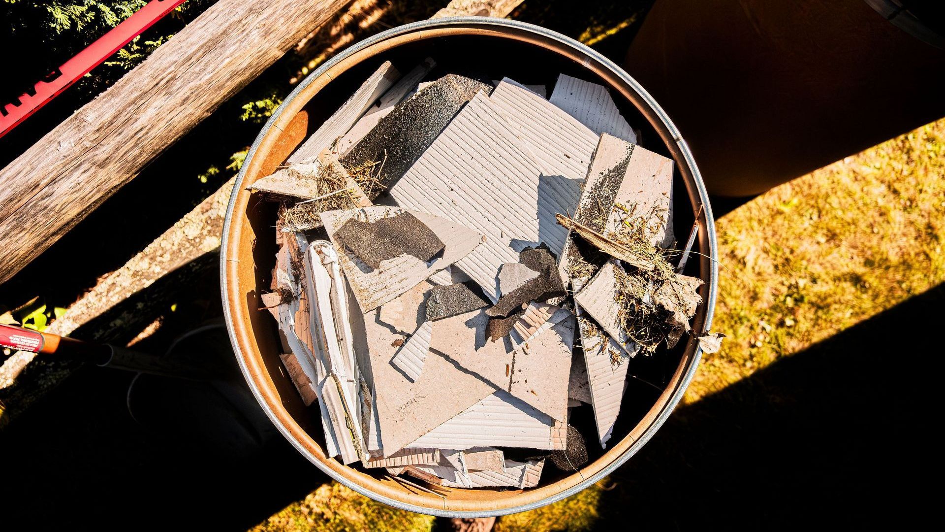 barrel filled with pieces of asbestos siding