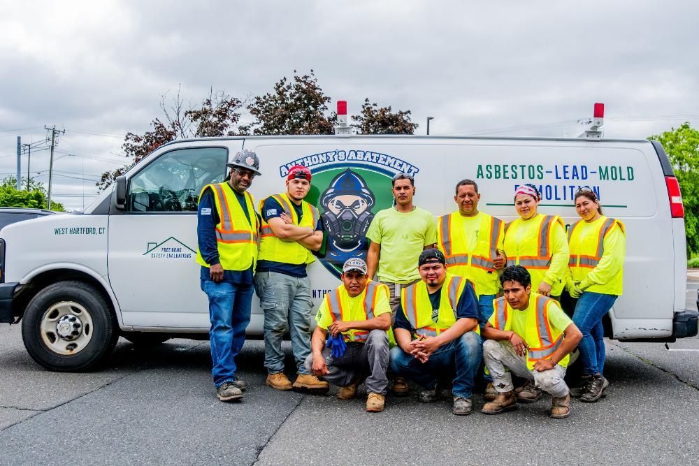 A group of demolition workers are posing for a picture in front of a van.