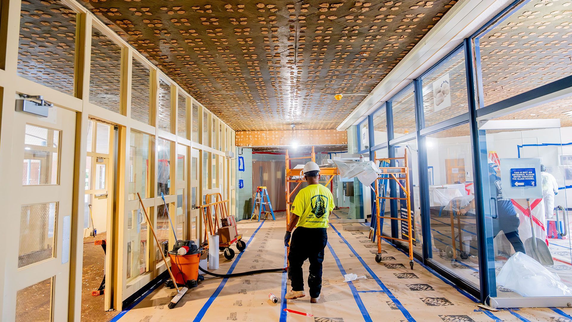 A man is walking down a hallway in a building under construction.