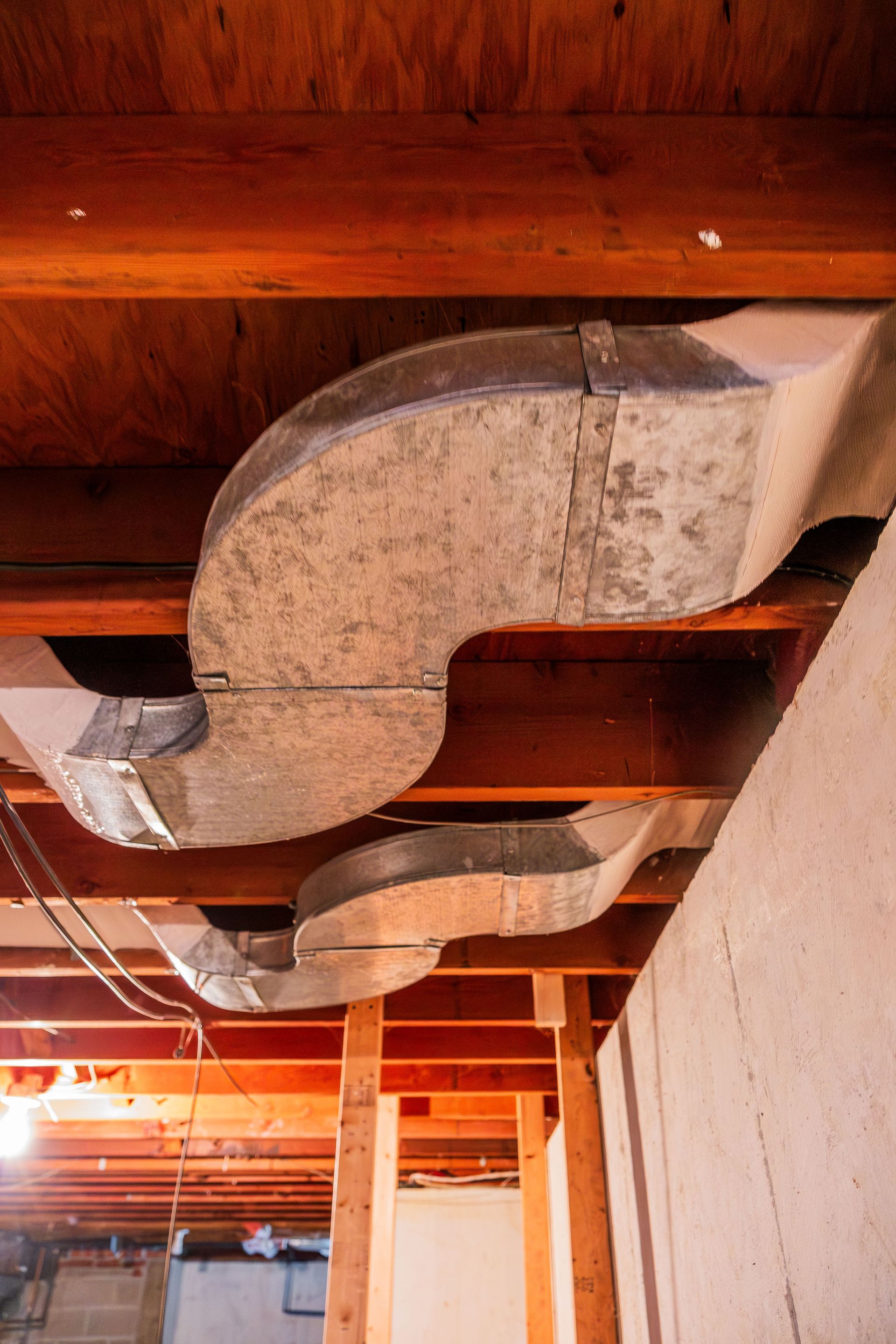 A bunch of metal pipes are hanging from the ceiling of a building.