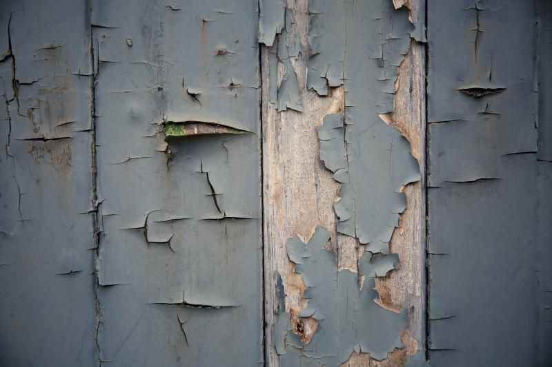 A close up of a wooden wall with peeling paint