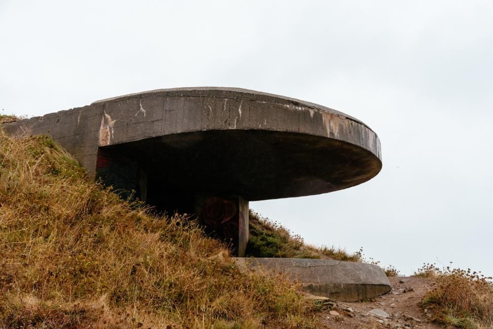 A large concrete structure is sitting on top of a grassy hill.