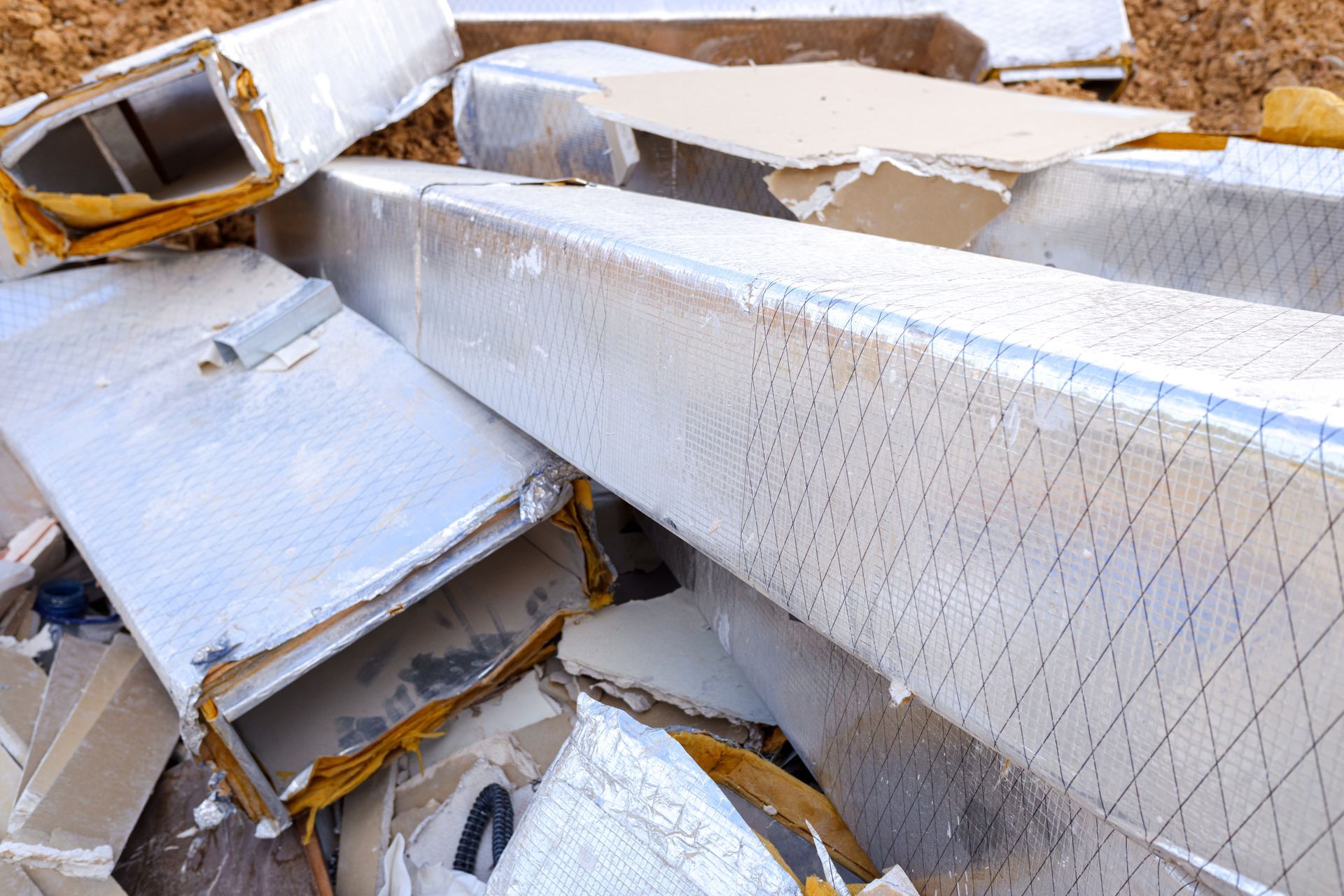 Heap of damaged, insulated ductwork and debris, likely construction waste.