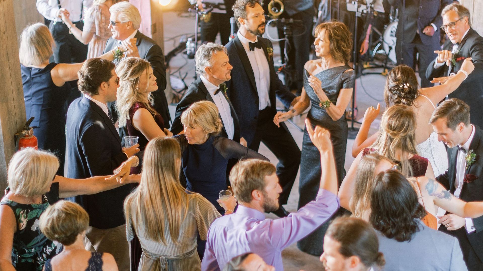 a large group of people are dancing at a wedding reception .