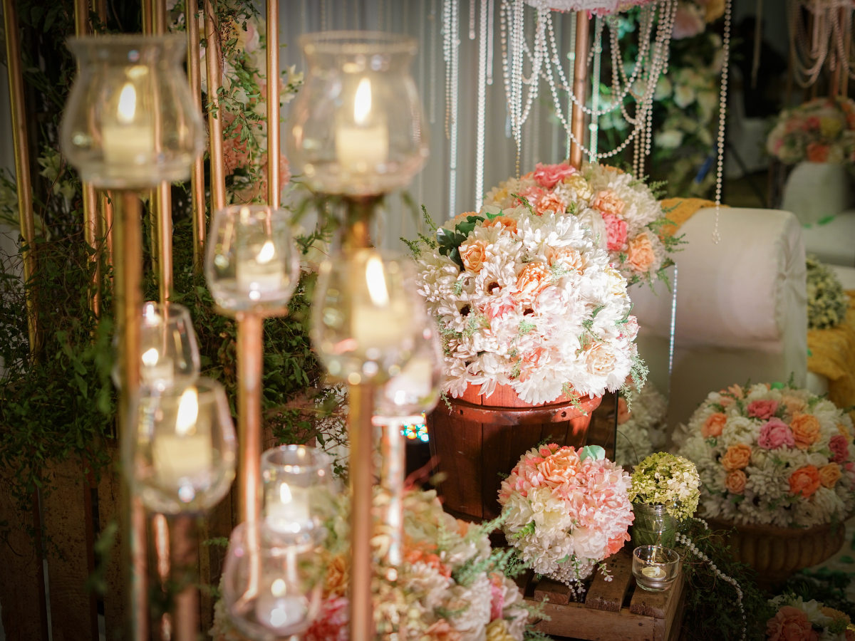 a display of flowers and candles with pearls hanging from the ceiling at a wedding reception