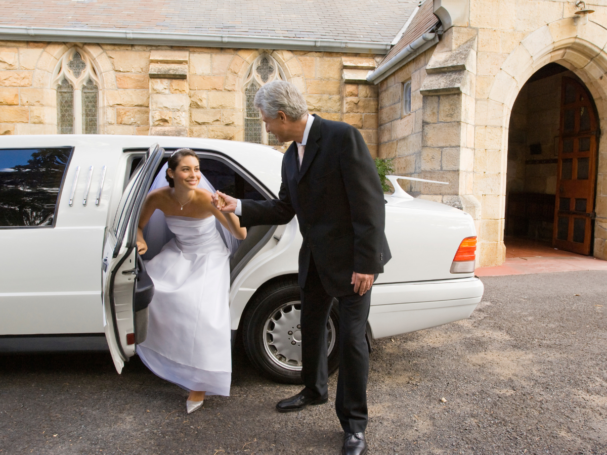 a man helps a bride out of a limousine
