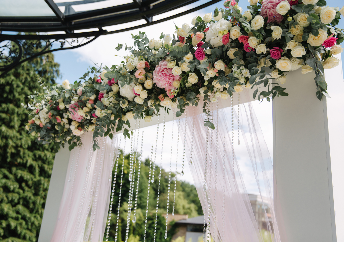 a white arch with flowers and pearls hanging from it