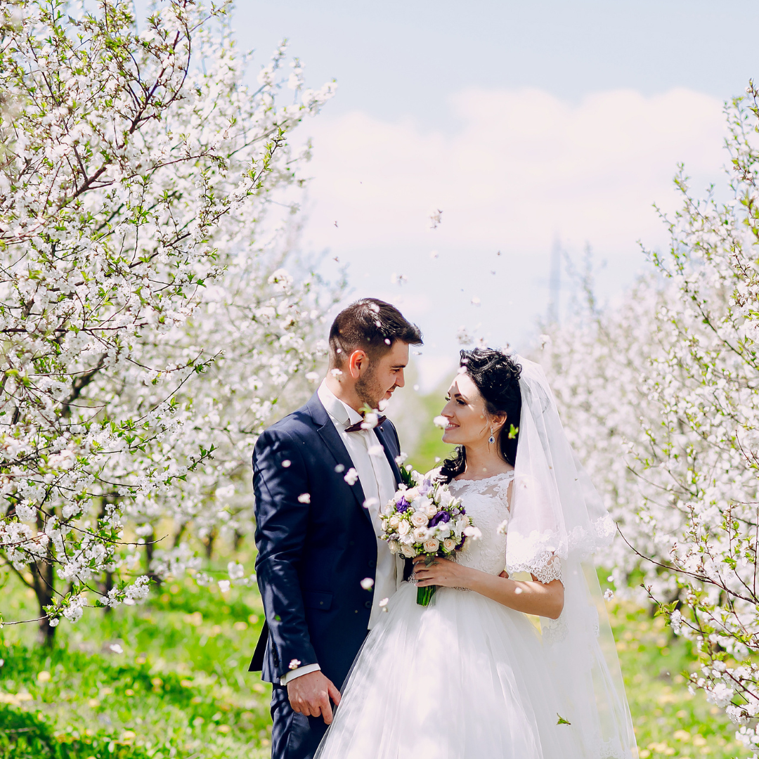 a bride and groom are standing in a field of flowers .
