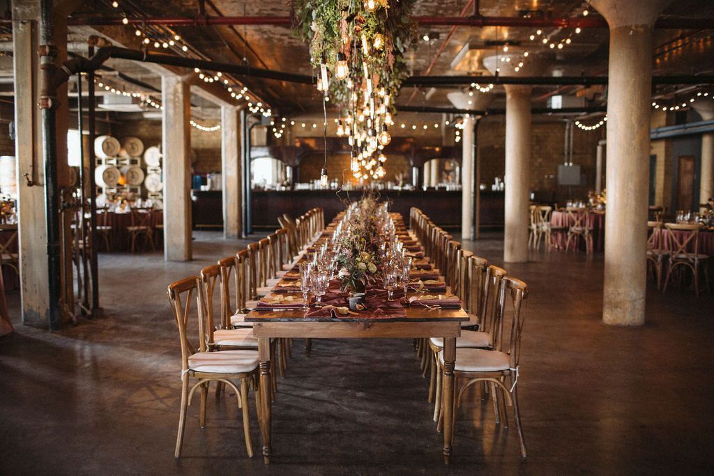 a long table in a large room with lots of chairs at a venue for a wedding in Detroit