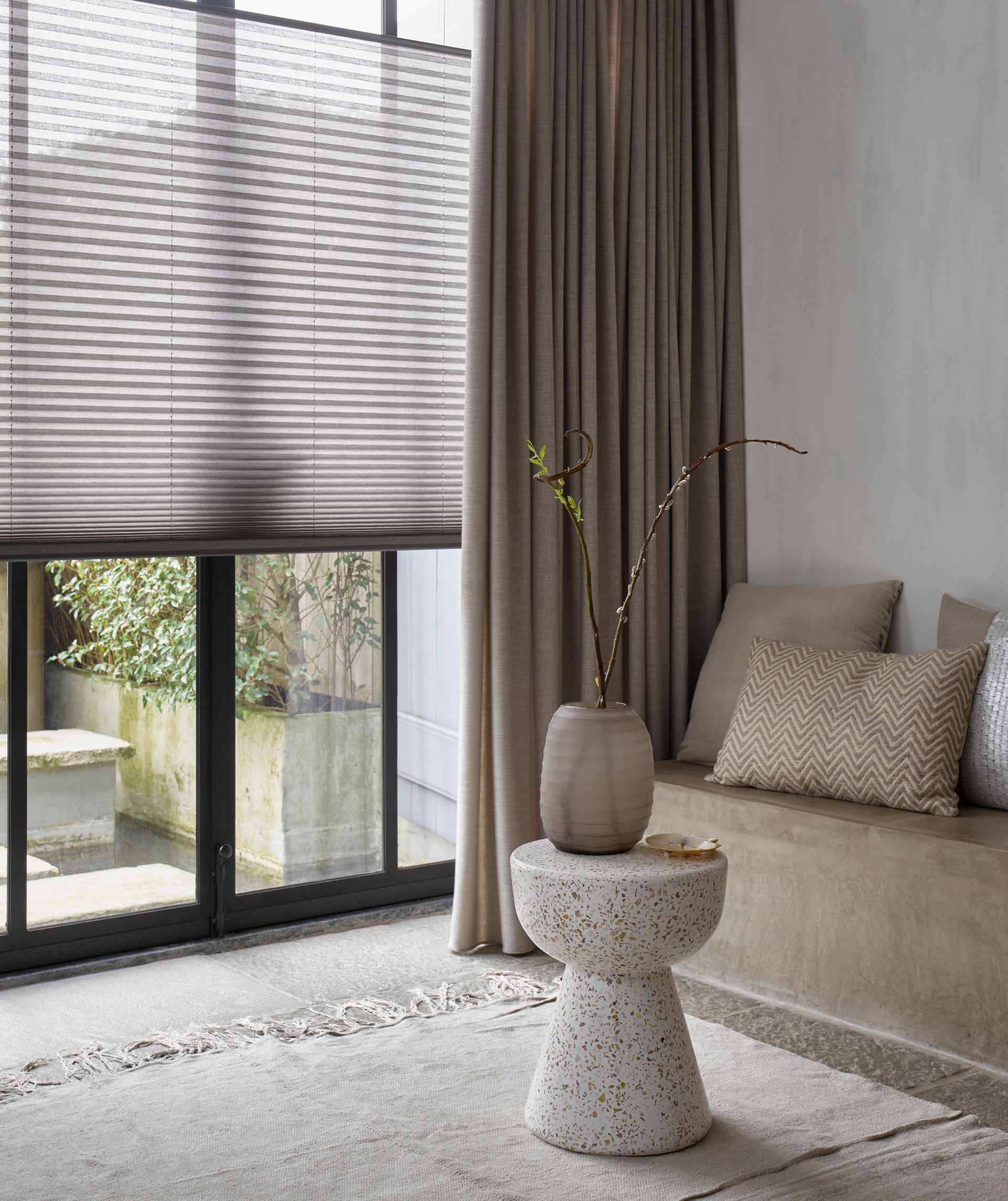 Person, der måler en grå persienne med et målebånd.