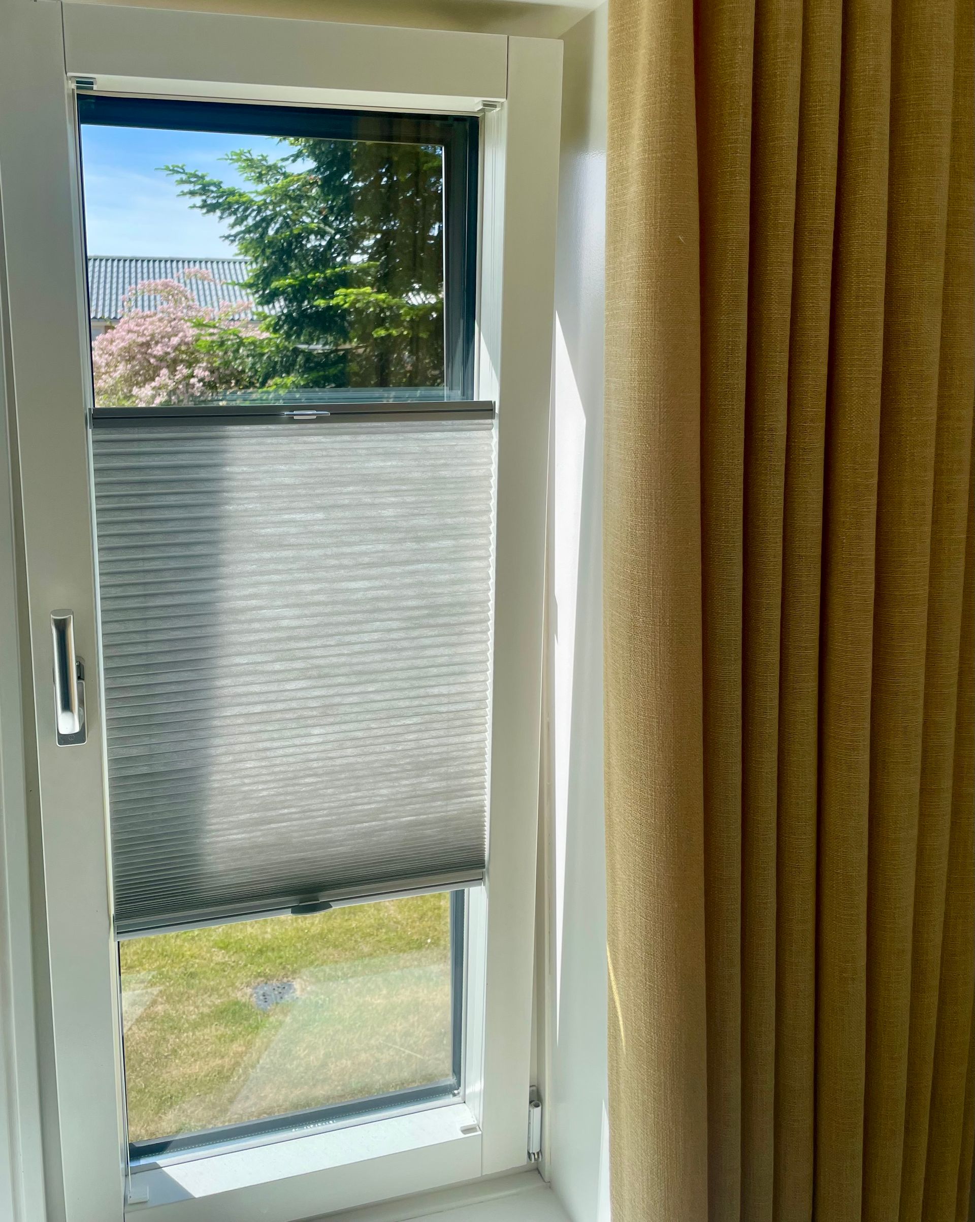 Brune plisserede persienner, lukkede, i en træramme.