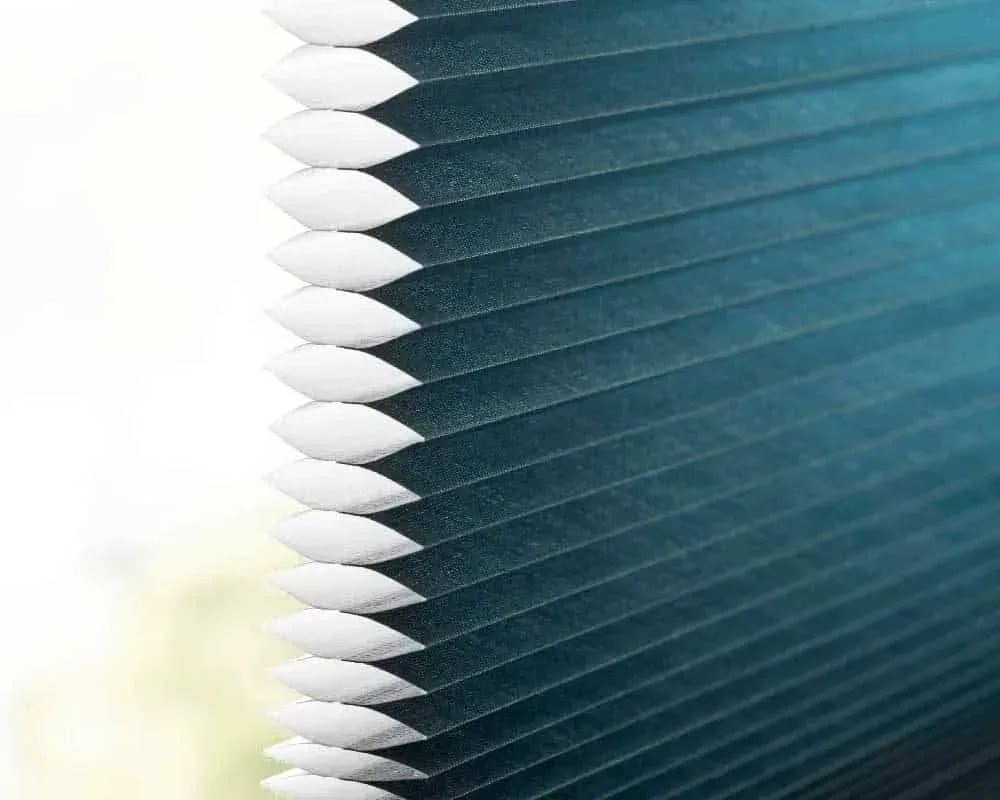 Blå plisseret vinduesskærm med hvide kanter, der delvist dækker et vindue.