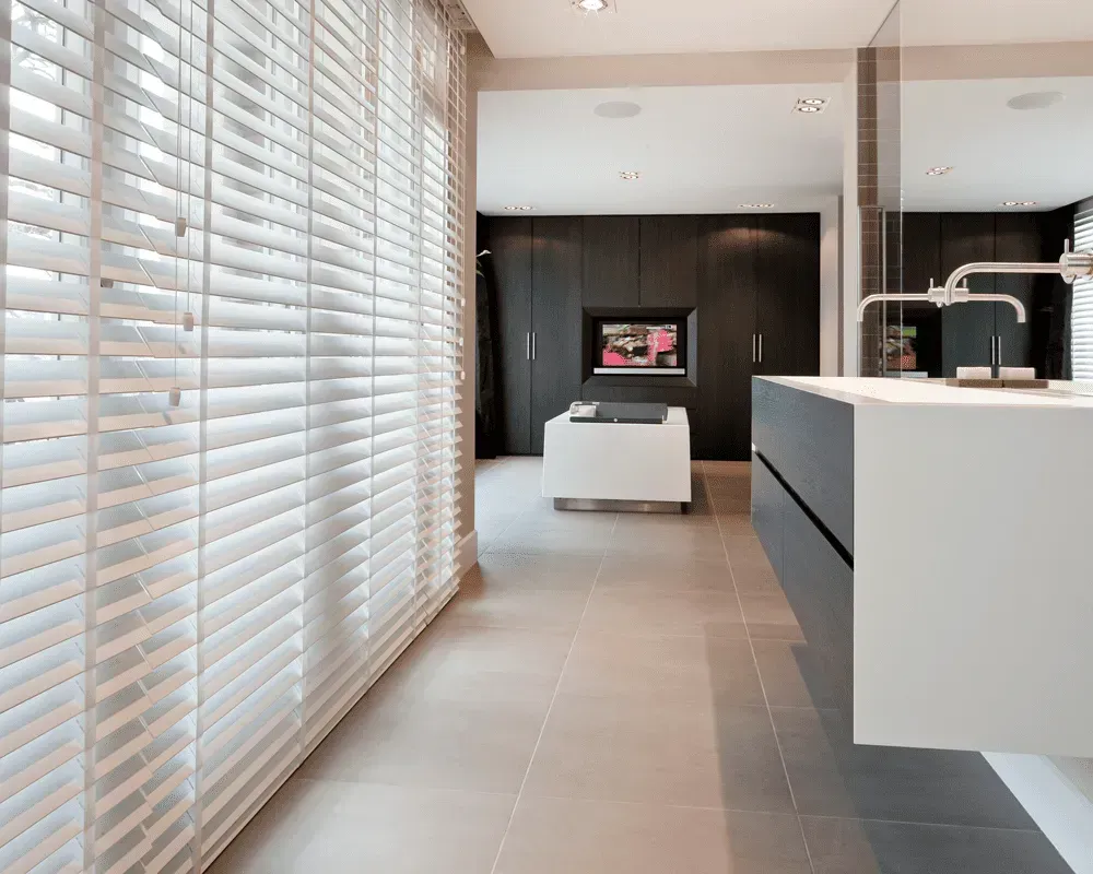 Moderne køkken med hvide persienner, gråt flisegulv og mørke skabe.