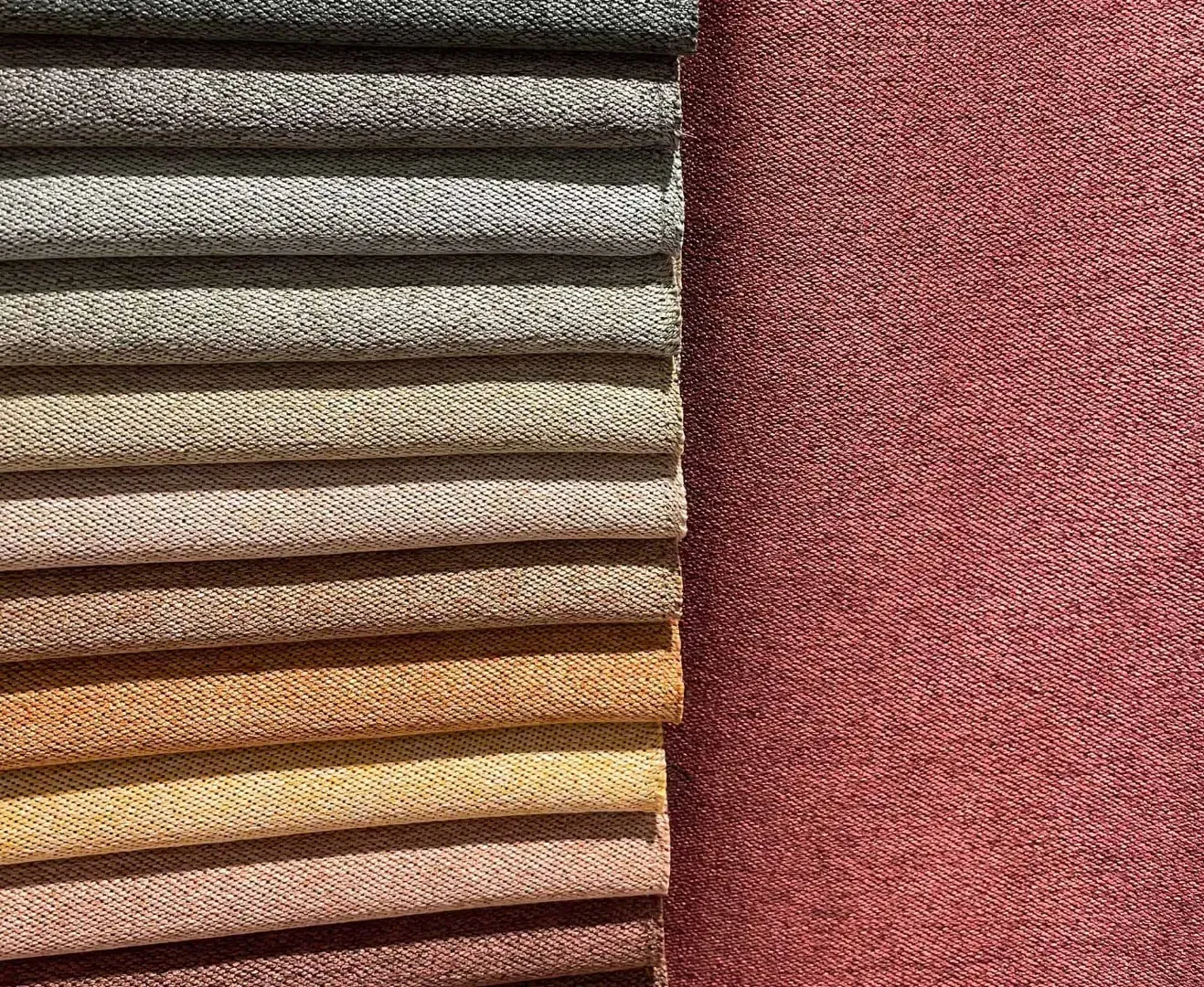 Stofprøver i neutrale nuancer og et mørkerødt tekstil.