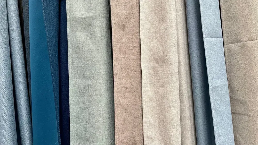 Nærbillede af stofprøver i nuancer af blå, grå og beige, vist lodret.