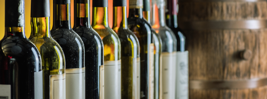 Row of wine bottles on a wooden shelf in a dimly lit cellar
