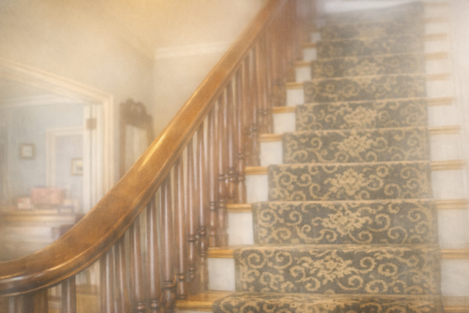 Dusty staircase with floral runner and wooden banister in a softly lit hallway
