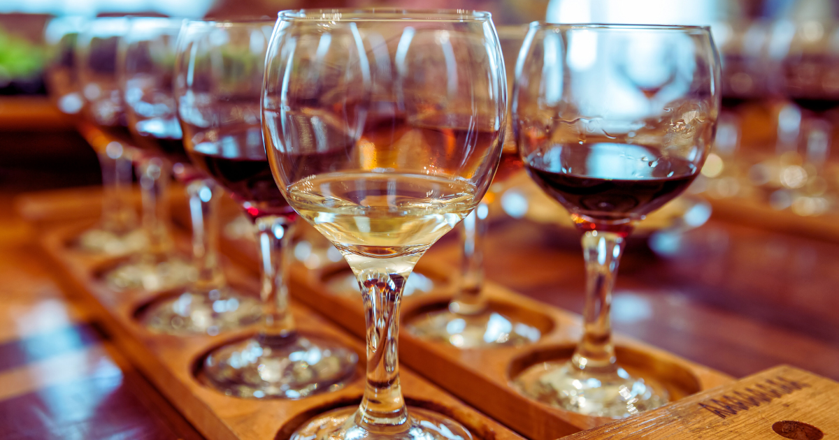 Wine glasses on wooden trays in a dimly lit tasting setting with warm reflections