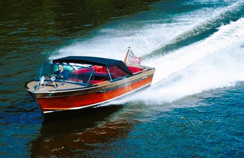Red speedboat racing across blue water, leaving a white wake, with a small American flag at the stern