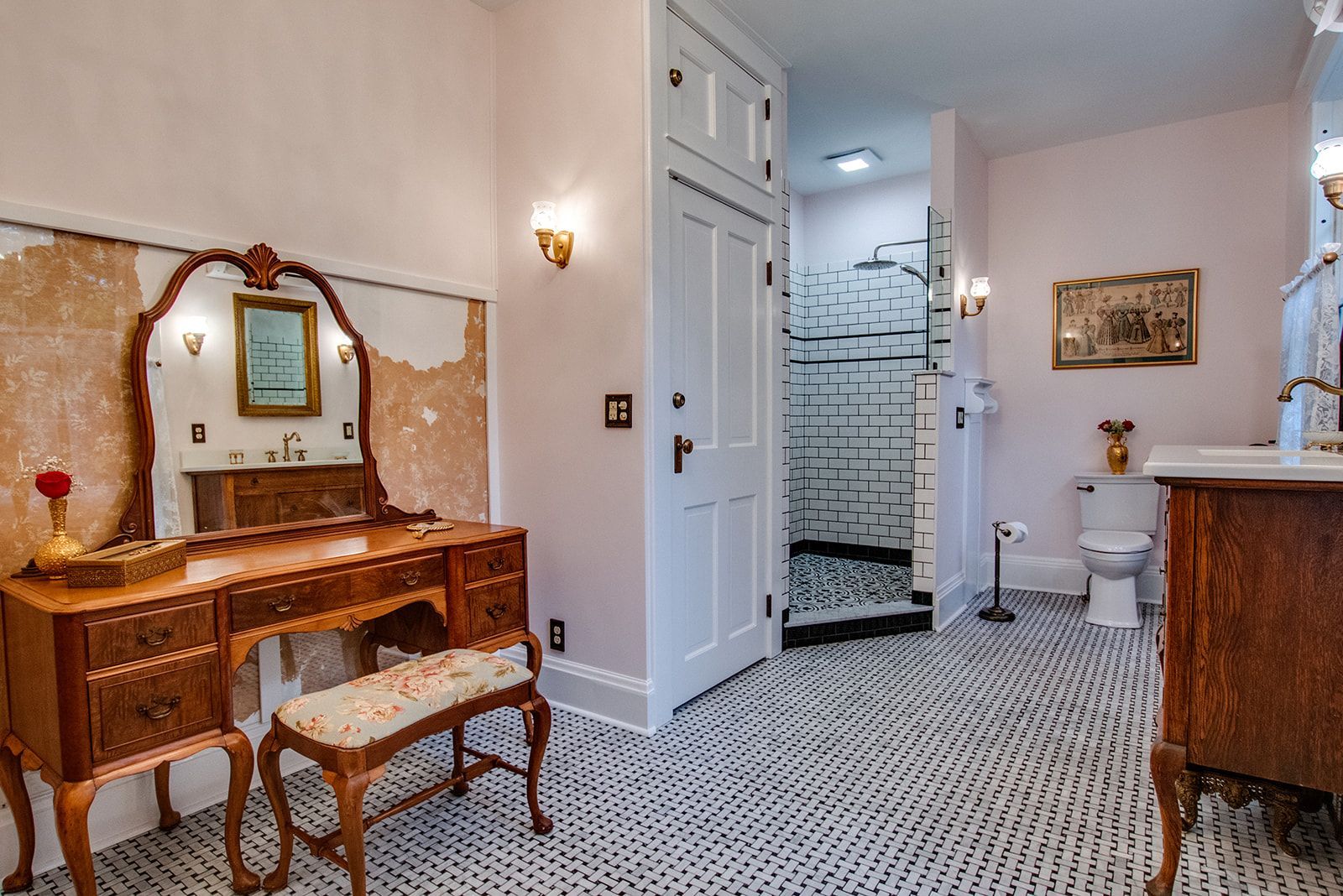 Elegant bathroom with vanity table, patterned floor, shower, and toilet in soft pink tones