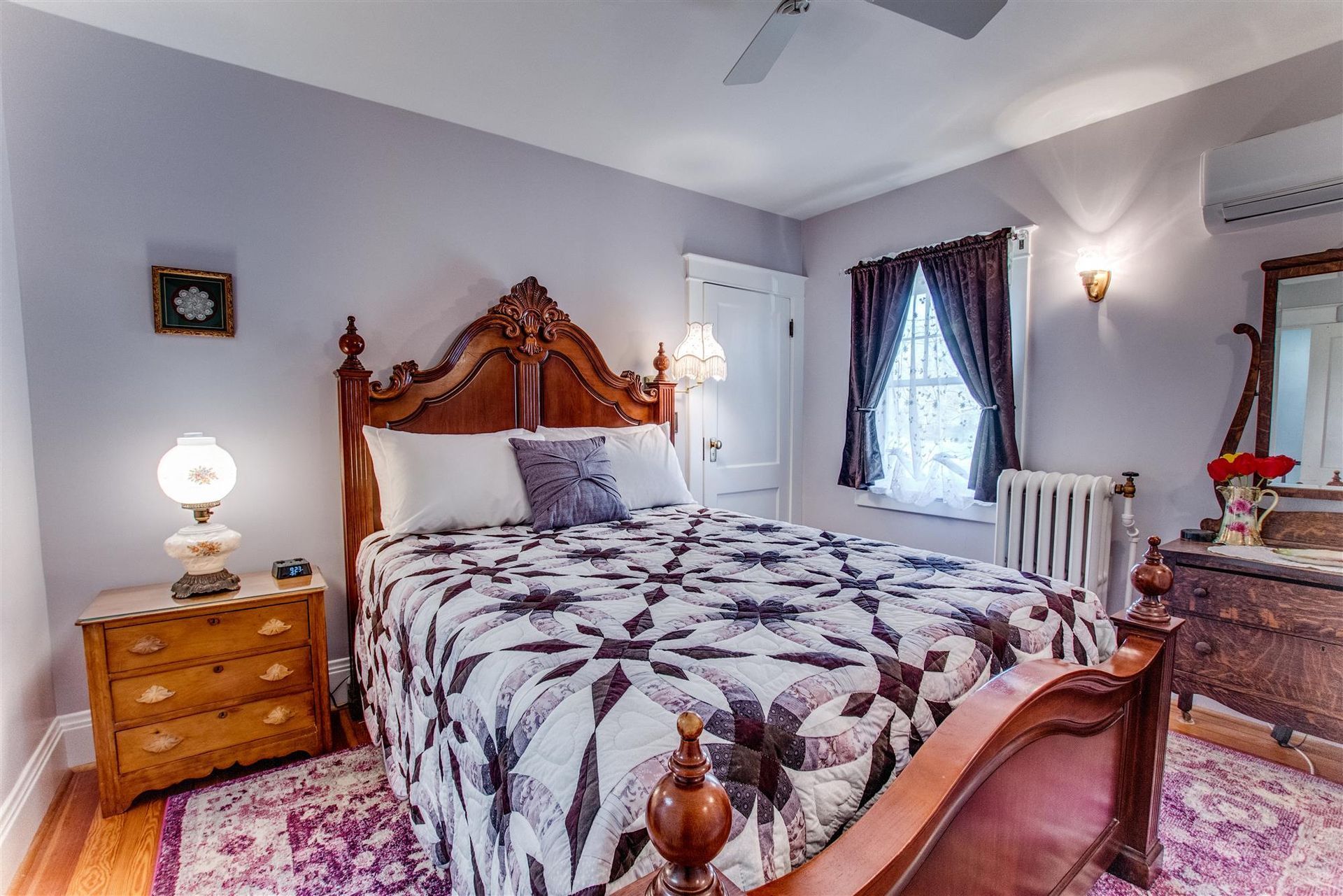 Elegant bedroom with a wooden bed, patterned bedding, bedside tables, and soft gray walls.