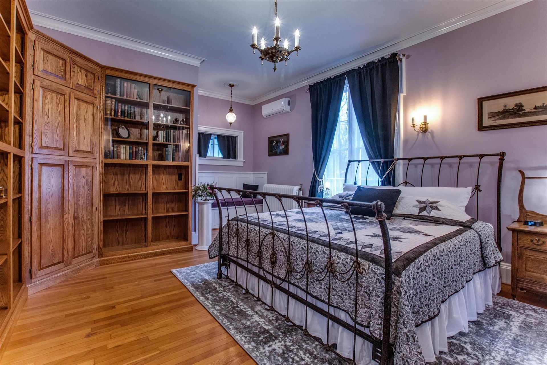 Elegant bedroom with a wrought-iron bed, wood cabinet, blue curtains, and hardwood floors