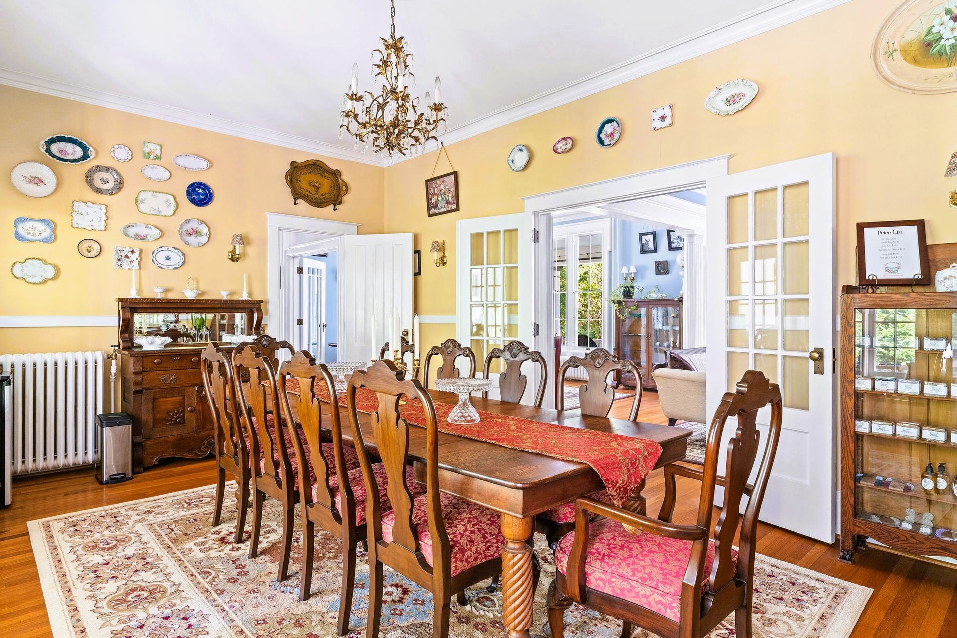 Elegant dining room with wooden table, chairs, chandelier, yellow walls, and china cabinets