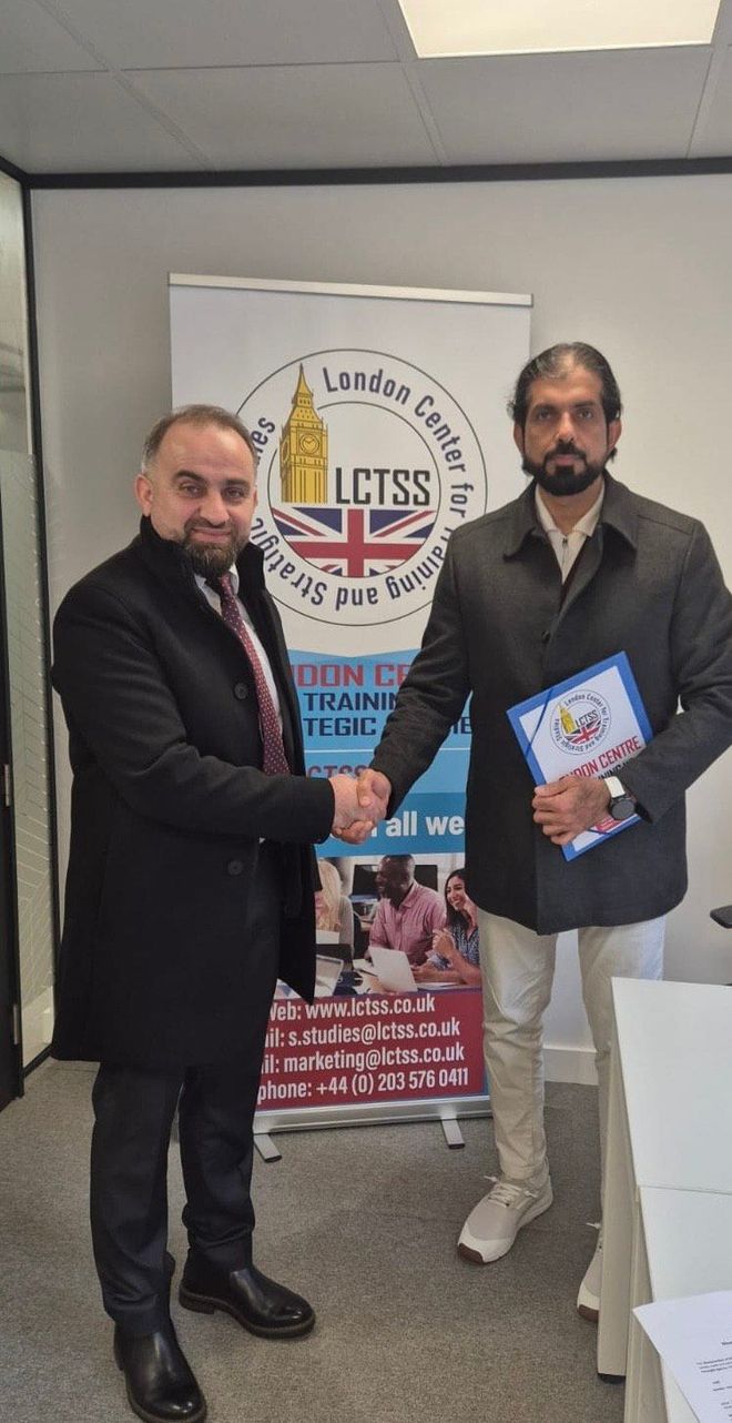 Two men are shaking hands in front of a sign that says lctss.