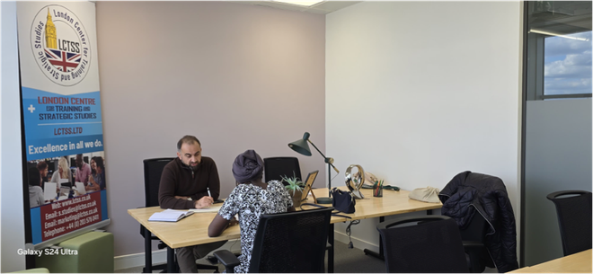 A man and a woman are sitting at a desk in an office.
