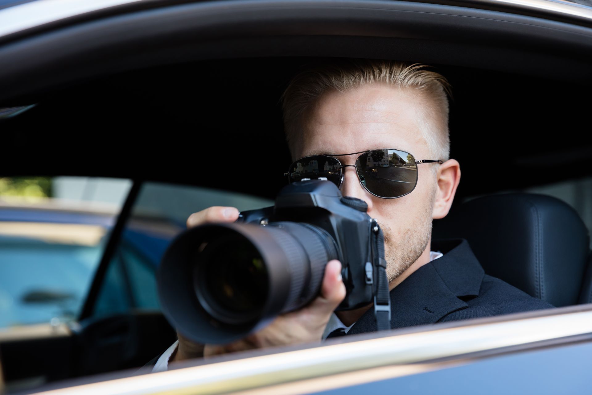 A man is sitting in a car taking a picture with a camera.