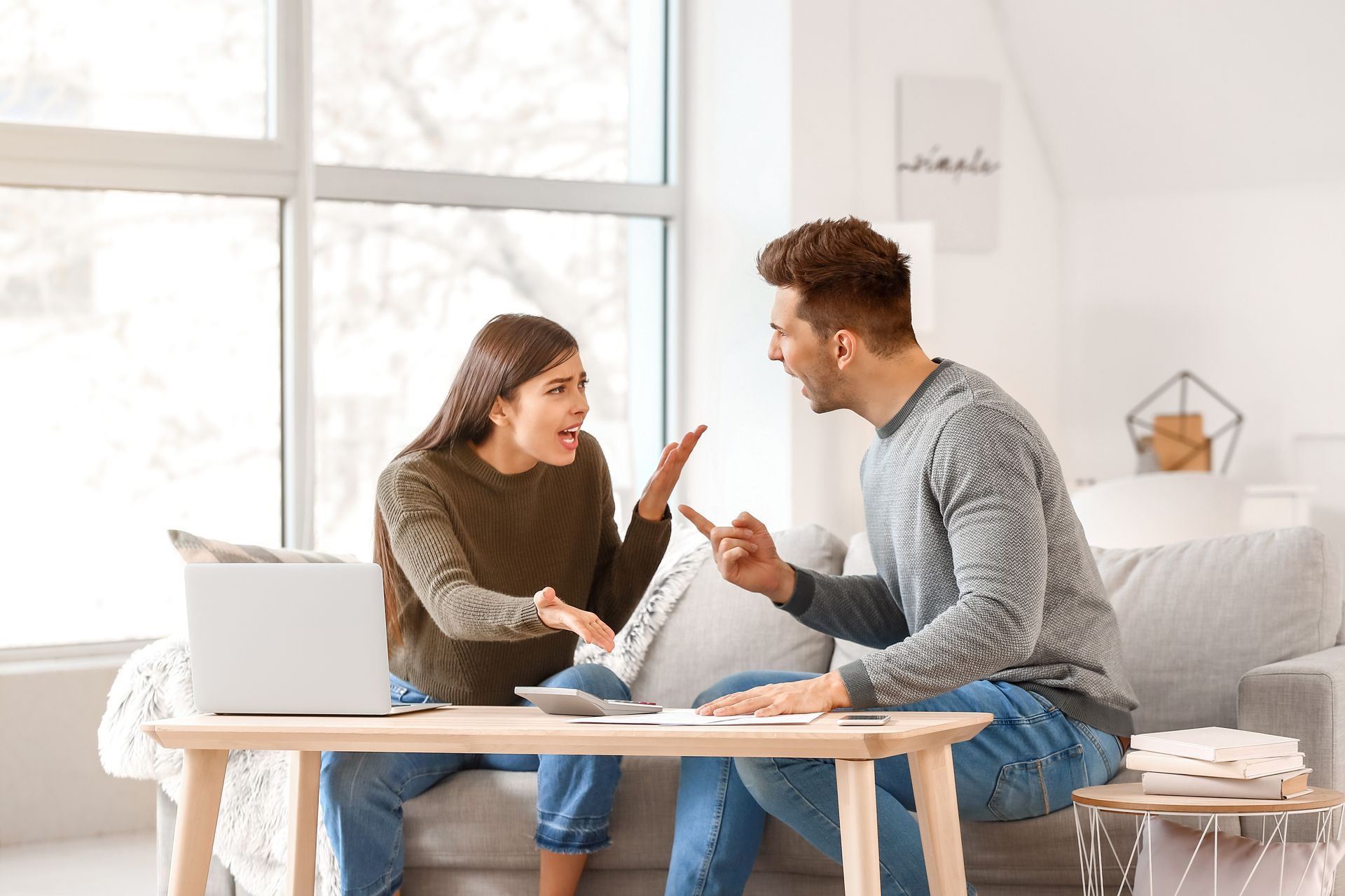 A man and a woman are sitting on a couch having an argument.