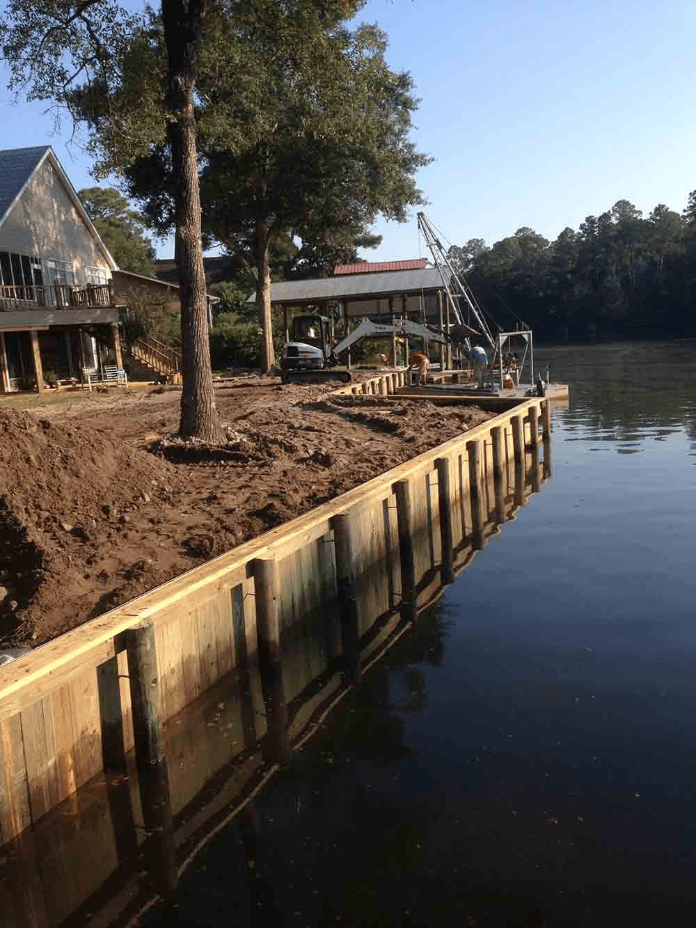 A house is sitting on the shore of a lake next to a wooden dock.