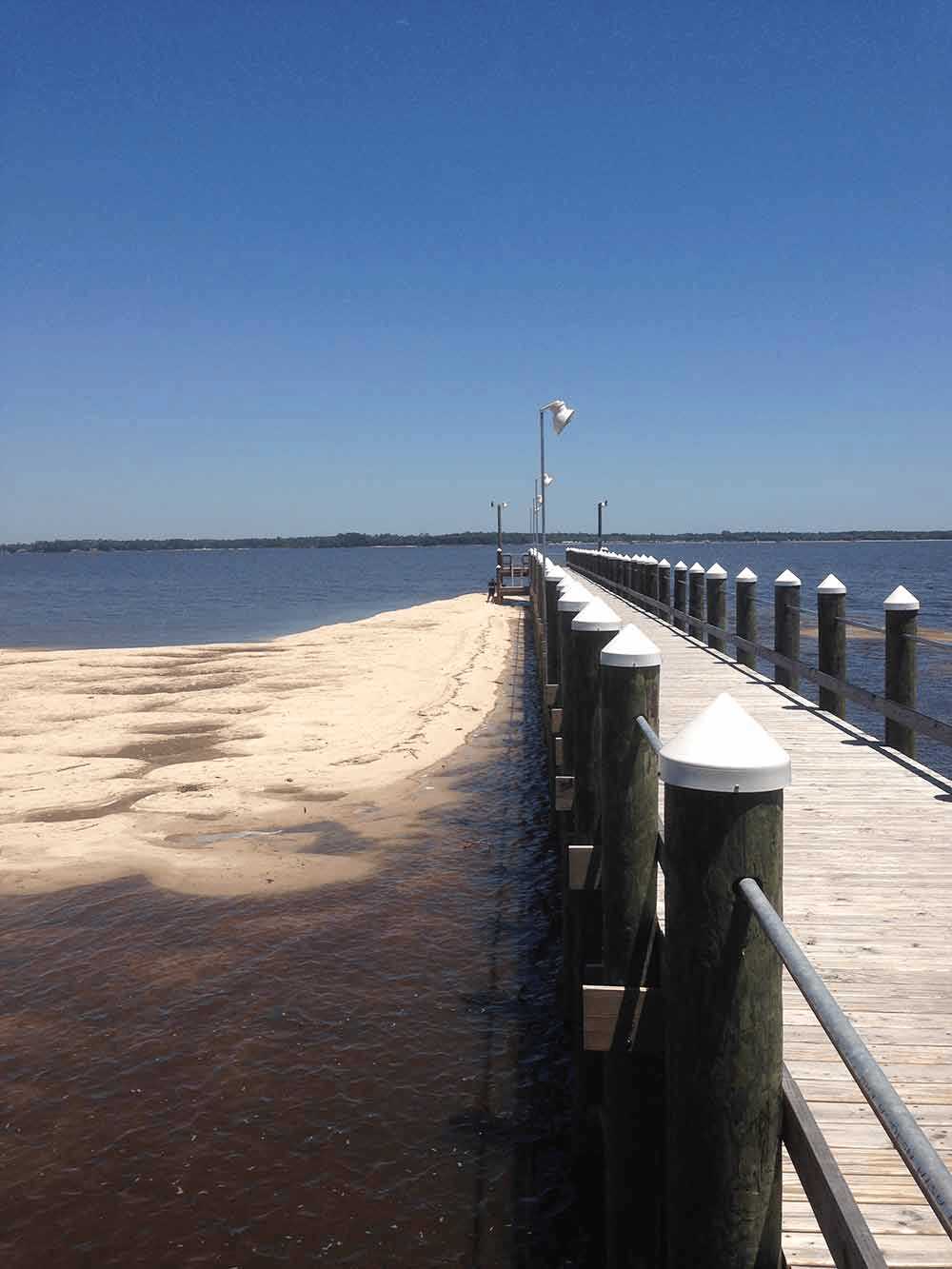 A wooden pier leading to a sandy beach