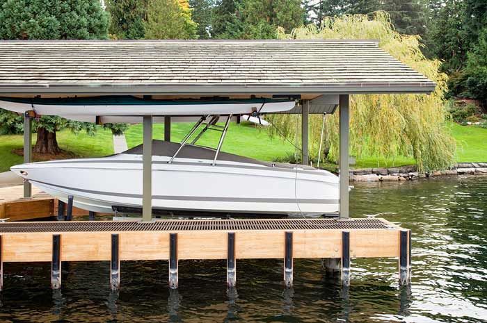 A boat is sitting under a covered dock on a lake.