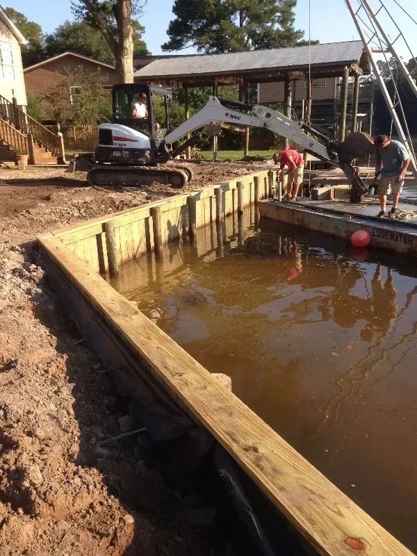 A bobcat excavator is being used to build a dock