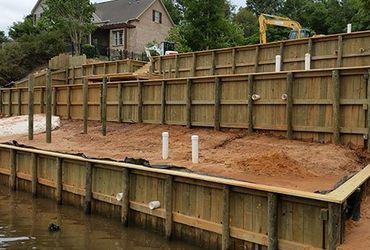 A wooden fence is being built next to a body of water.