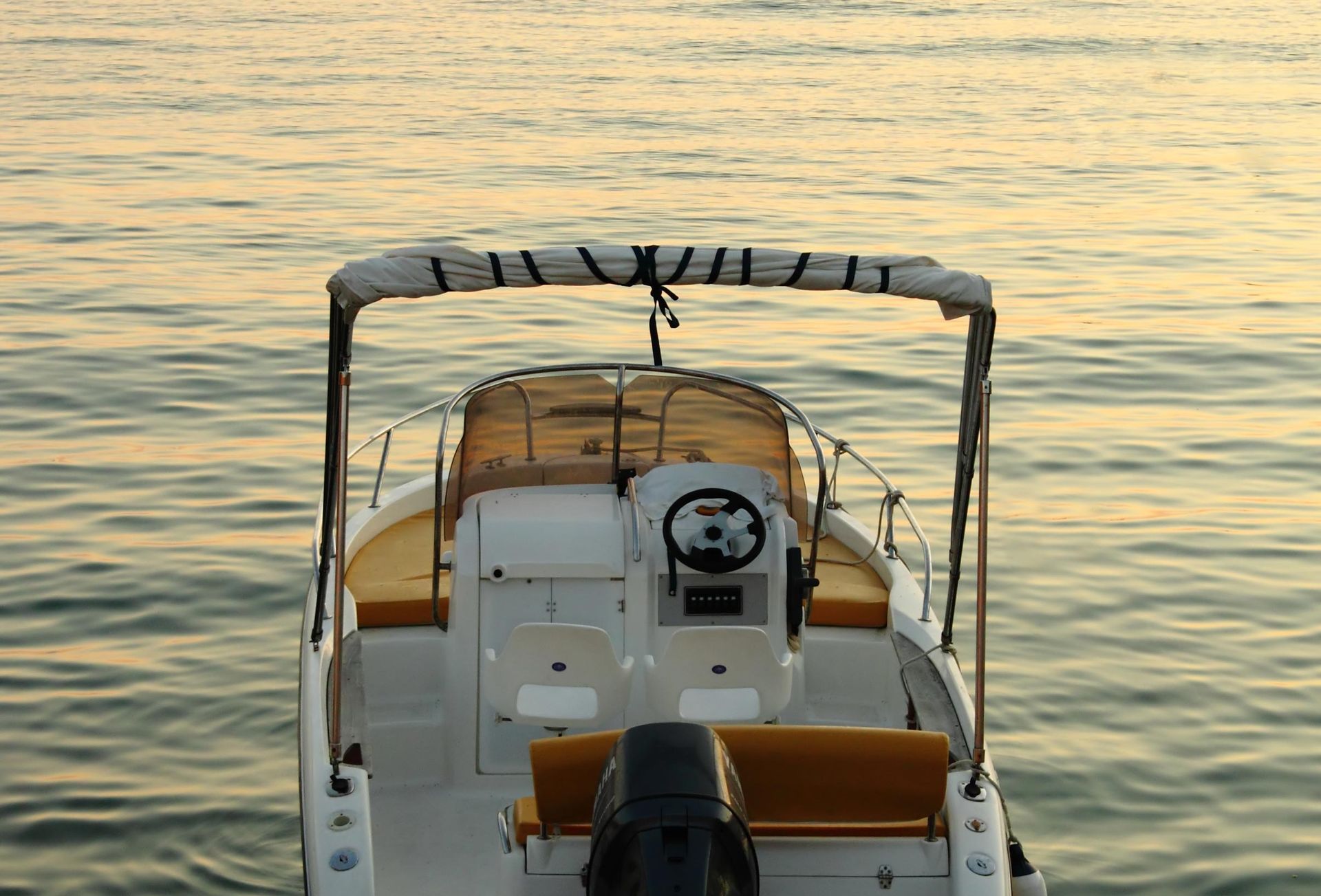 The front of a boat in the water with a steering wheel