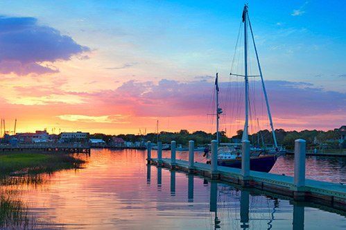 A sailboat is docked at a dock at sunset.